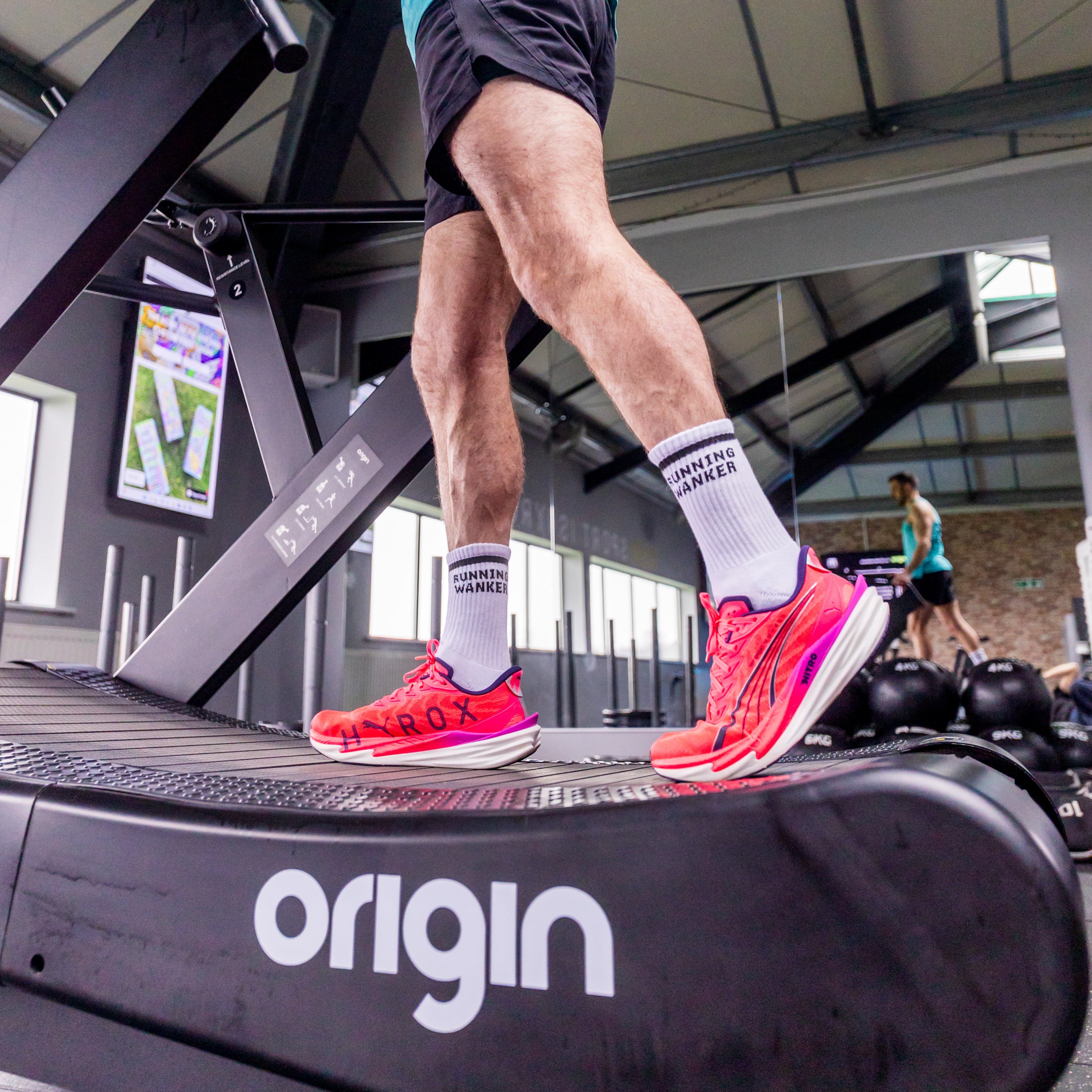Person using a treadmill with 'origin' branding in a gym setting